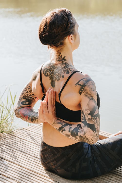 匿名纹身的女人在反向祈祷姿势打坐 · 免费素材图片