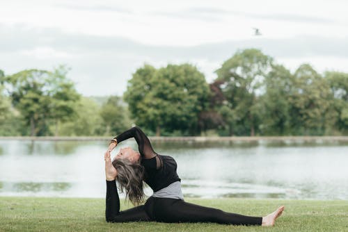 在河岸上练瑜伽时伸展双腿的赤脚女人 · 免费素材图片
