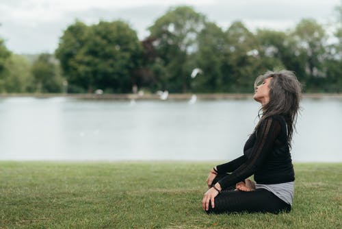 正念的女人坐在河边的莲花姿势 · 免费素材图片