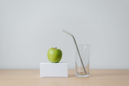 在空的玻璃用稻草附近的盒子上的青苹果 · 免费素材图片