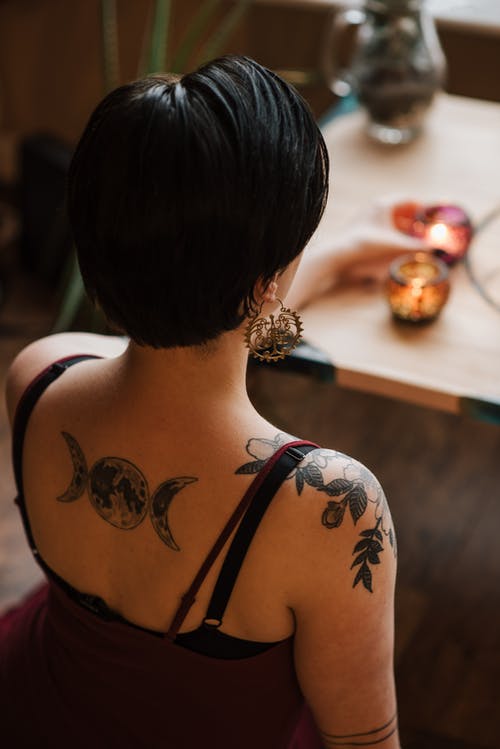 不露脸的纹身占卜者与燃烧的蜡烛在家里 · 免费素材图片