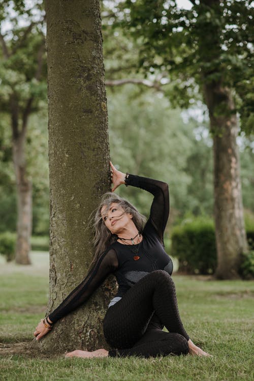 梦幻般的女人在树干附近表演坐着扭姿势 · 免费素材图片