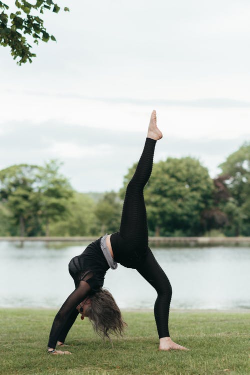 无法识别女人与抬高的腿，在岸上练瑜伽 · 免费素材图片