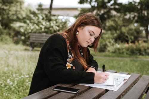 在公园里集中的女人在纸上写笔记 · 免费素材图片