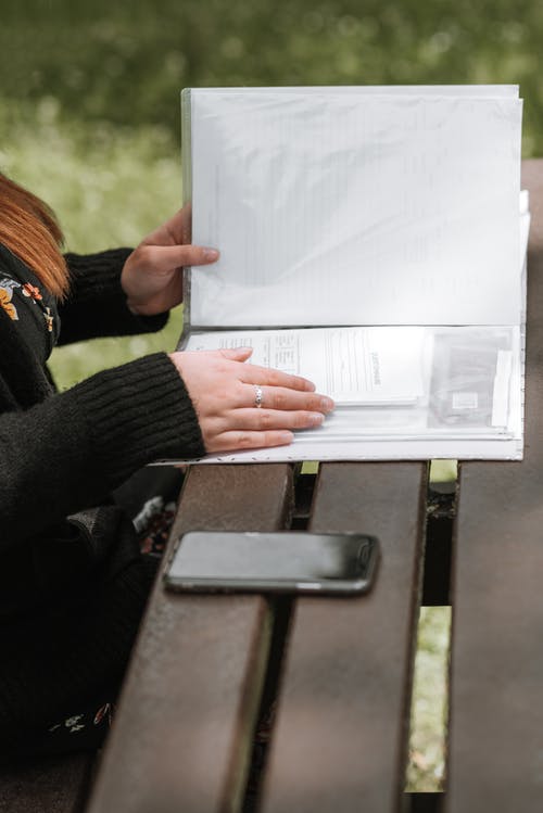 裁剪无法识别女人在公园里的文件夹中阅读文档 · 免费素材图片