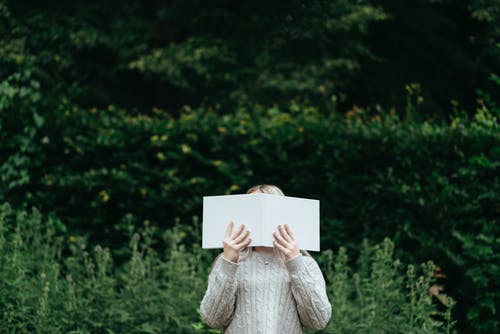 女人在自然界中读书时遮住脸 · 免费素材图片