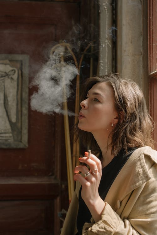 米色大衣抽烟的女人 · 免费素材图片
