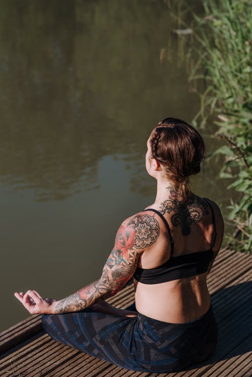 不可识别的纹身的女人在湖边码头上沉思 · 免费素材图片