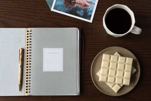 靠近咖啡和白巧克力的笔记本 · 免费素材图片