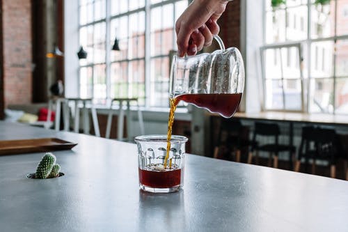 在透明的水杯上倒红色液体的人 · 免费素材图片