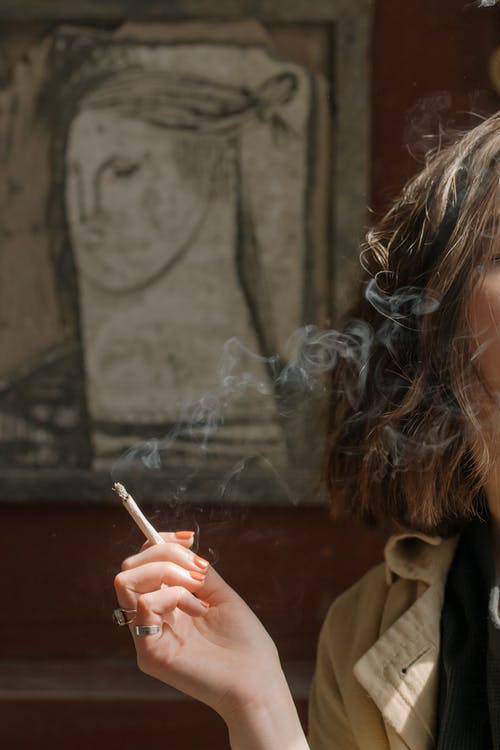 棕色外套抽烟的香烟的女人 · 免费素材图片