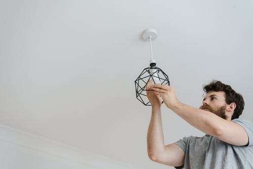 男子将灯泡拧入灯 · 免费素材图片