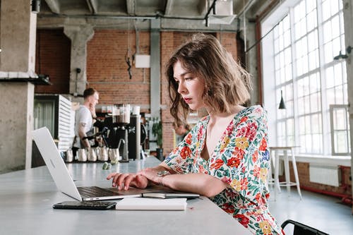 使用macbook Air的红色白色和蓝色花衬衫的女人 · 免费素材图片