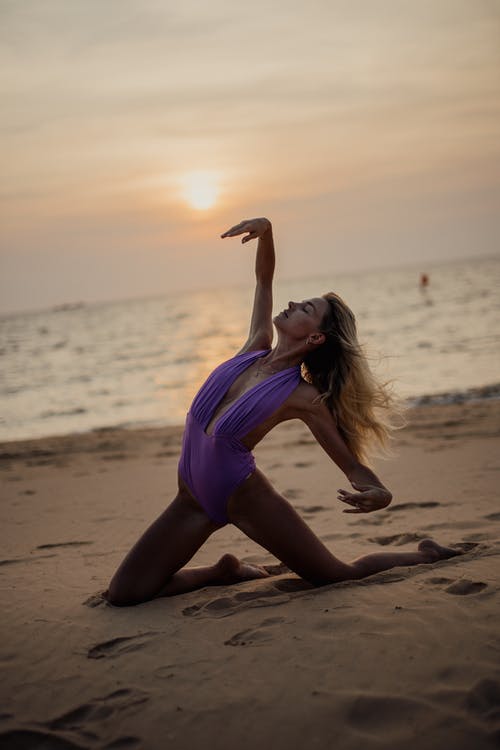 紫色背心和黑色内裤跪在海滩岸边的女人 · 免费素材图片