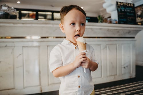 白色纽扣衬衫吃冰淇淋的男孩 · 免费素材图片