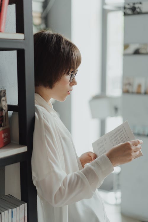 白色长袖衬衫阅读书中的女人 · 免费素材图片