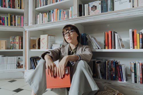 拿着红宝书的灰色外套的女人 · 免费素材图片