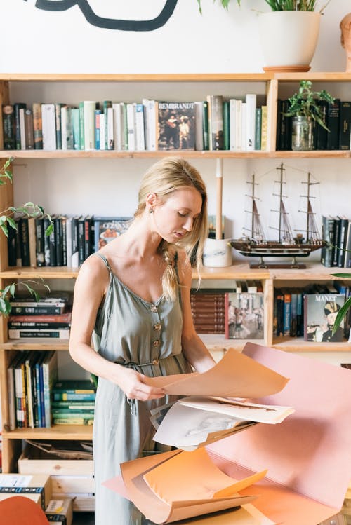 拿着白色打印机纸的白色背心的女人 · 免费素材图片