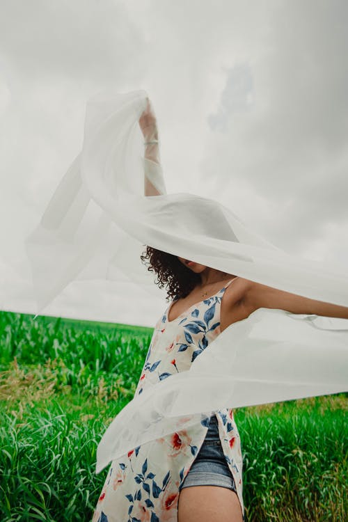 躺在绿草地上的白色和蓝色的花裙子的女人 · 免费素材图片