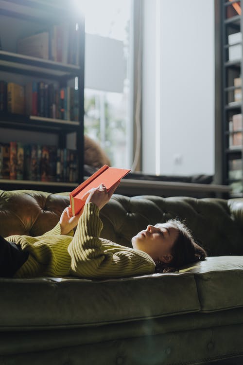 躺在黑色的沙发上的黄色长袖衬衫的女人 · 免费素材图片