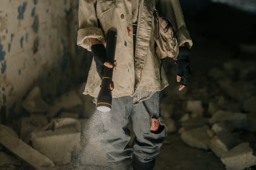 拿着黑色步枪的棕色夹克和蓝色牛仔牛仔裤的人 · 免费素材图片