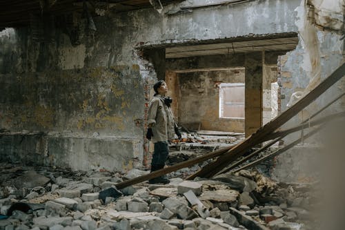 棕色夹克的人在灰色混凝土建筑上行走 · 免费素材图片