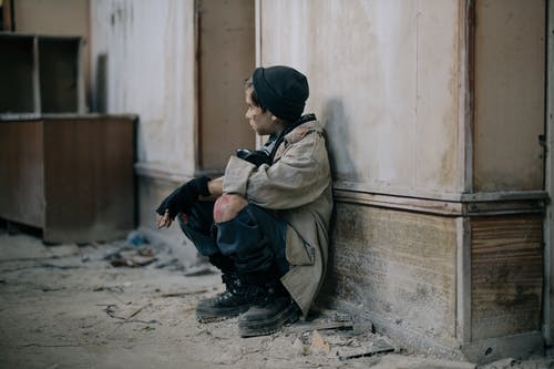 棕色外套和黑色的裤子，坐在混凝土墙上的男人 · 免费素材图片