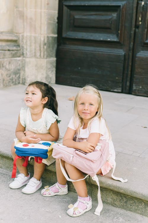 2个女孩坐在红色的塑料椅子上 · 免费素材图片