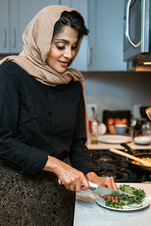 黑夹克拿着刀切食物的女人 · 免费素材图片