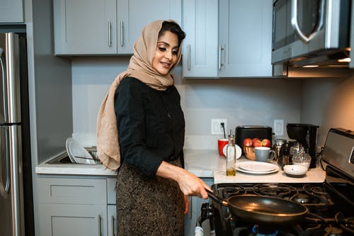 在现代厨房中用煎锅满足阿拉伯语的女人 · 免费素材图片