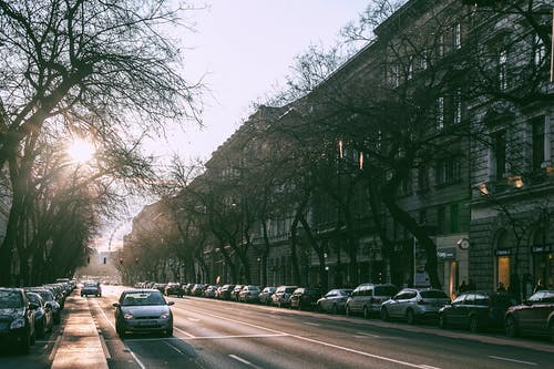 宽直的道路，在阳光明媚的早晨在城市景观中停放的汽车 · 免费素材图片