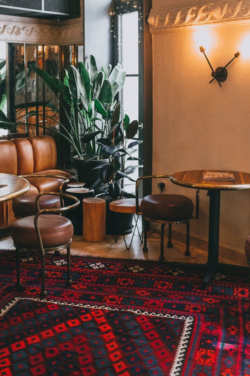 用木桌和皮椅装饰着古董地毯的时尚咖啡馆的内部 · 免费素材图片
