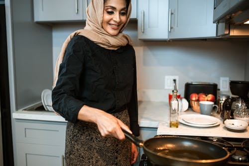 在现代的厨房里做饭的作物高兴的族裔女人 · 免费素材图片
