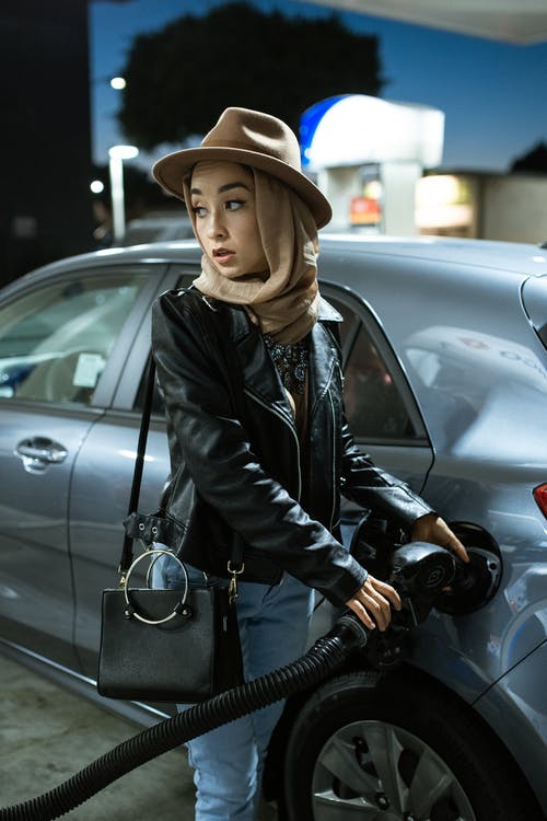 黑色皮夹克和棕色帽子站在黑色汽车旁边的人 · 免费素材图片