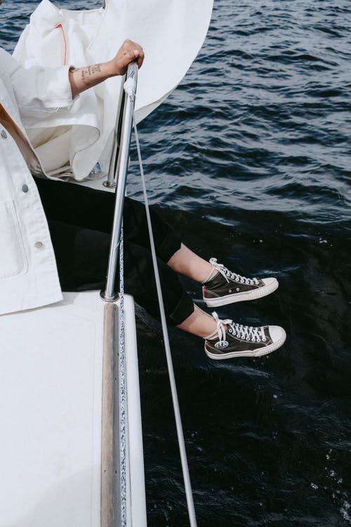 白船上的黑色和白色运动鞋的人 · 免费素材图片