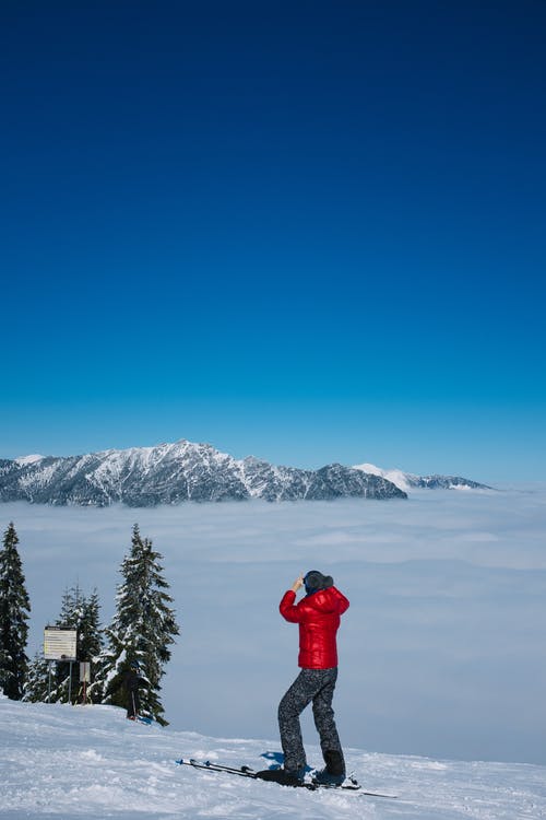 匿名的滑雪者考虑在蓝蓝的天空下的雪山 · 免费素材图片