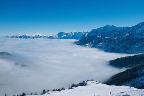 雪山与树木在大雾天在蓝蓝的天空下 · 免费素材图片