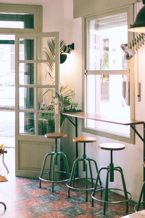 靠近窗口的木制柜台和凳子的时尚咖啡馆的内部 · 免费素材图片