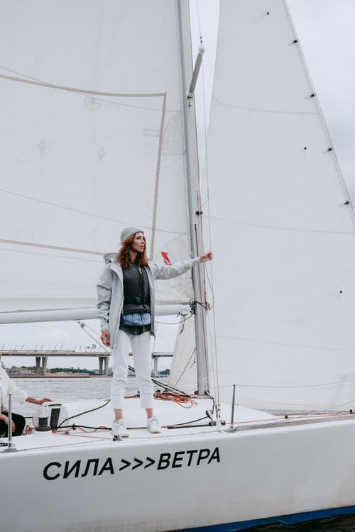 蓝色牛仔夹克和白色的裤子，站在白船上的女人 · 免费素材图片