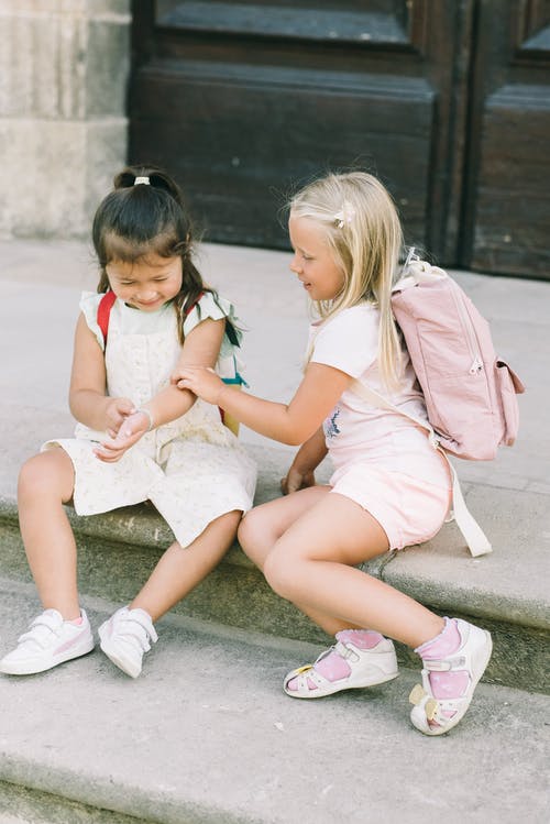 2个女孩坐在水泥地上 · 免费素材图片