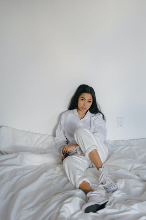 休息在床上的白色穿戴的亚裔妇女 · 免费素材图片