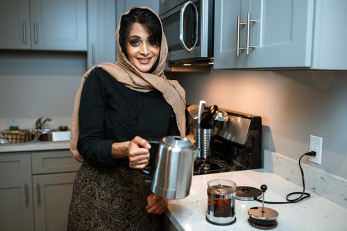 拿着不锈钢投手的黑夹克的女人 · 免费素材图片