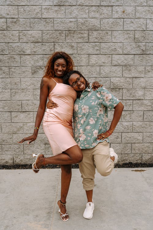 白色管礼服的女人拥抱白色和蓝色花裙子的女人 · 免费素材图片