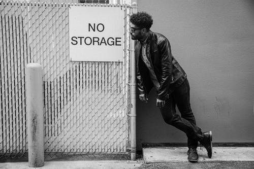 穿黑夹克的男人倚在墙上 · 免费素材图片