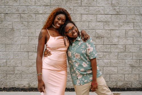 2名妇女站在棕色砖墙旁边 · 免费素材图片