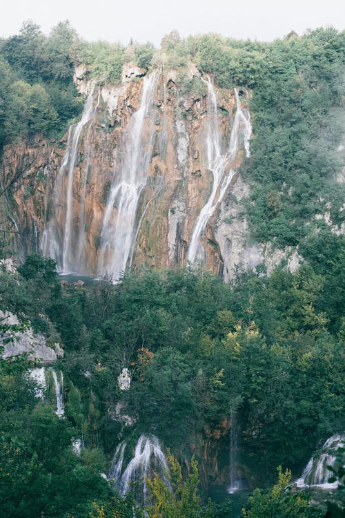 如诗如画的瀑布流淌在岩石深谷的绿色茂密森林中 · 免费素材图片