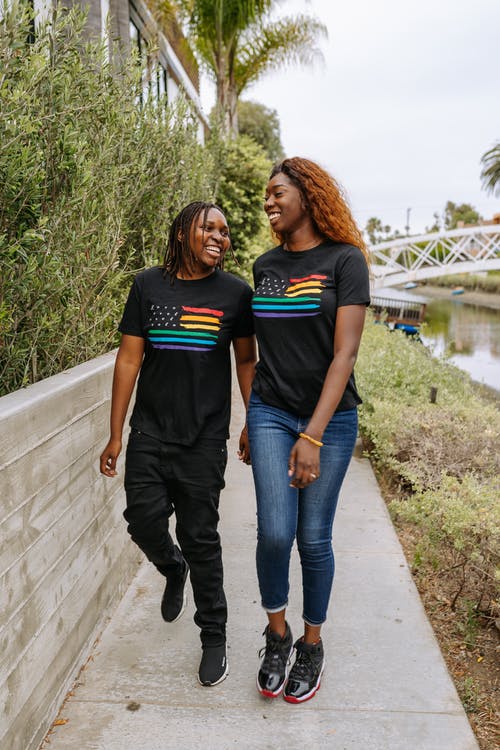 黑色t恤和蓝色牛仔牛仔裤的女人站在蓝色牛仔牛仔裤的女人旁边 · 免费素材图片