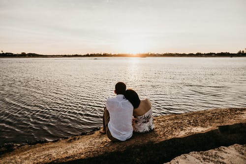 恩爱夫妻在河海岸上休息，享受日落 · 免费素材图片