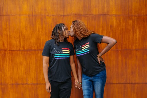 男人和女人站在棕色的木墙旁边 · 免费素材图片