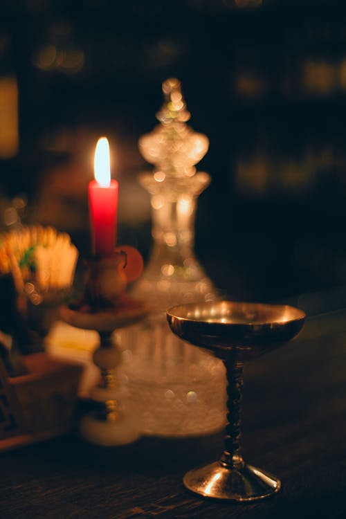 在教堂里的金属碗和玻璃水瓶附近燃烧的蜡烛 · 免费素材图片